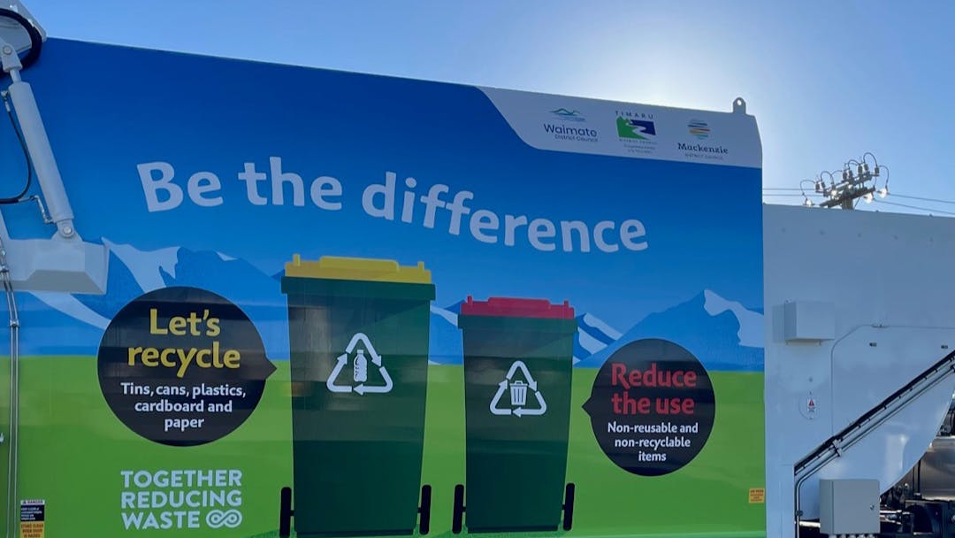 Side of rubbish collection truck showing Let's Recycle and Reduce the Use messages
