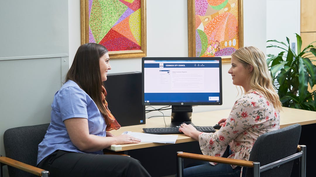 Council Staff sitting and helping community member at a computer