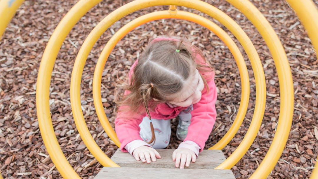 Child climbing on yellow spiral play equipment outside
