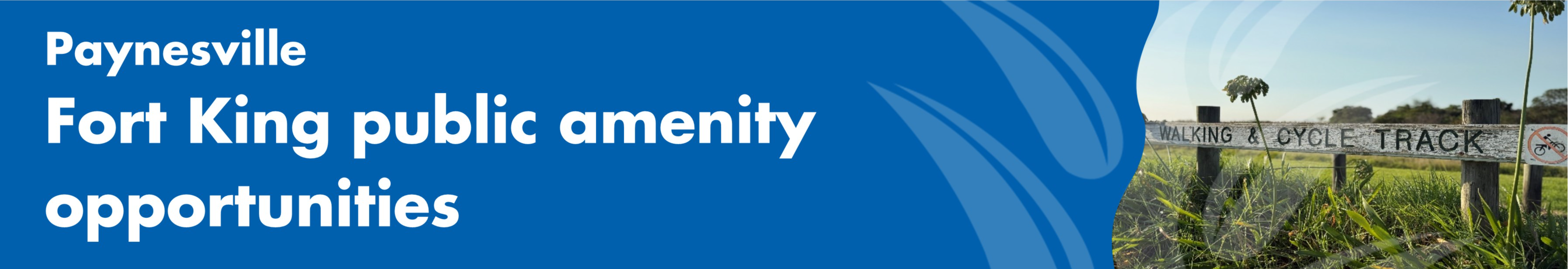 A grassy area with a seat overlooking a lake and mountains on an overcast day