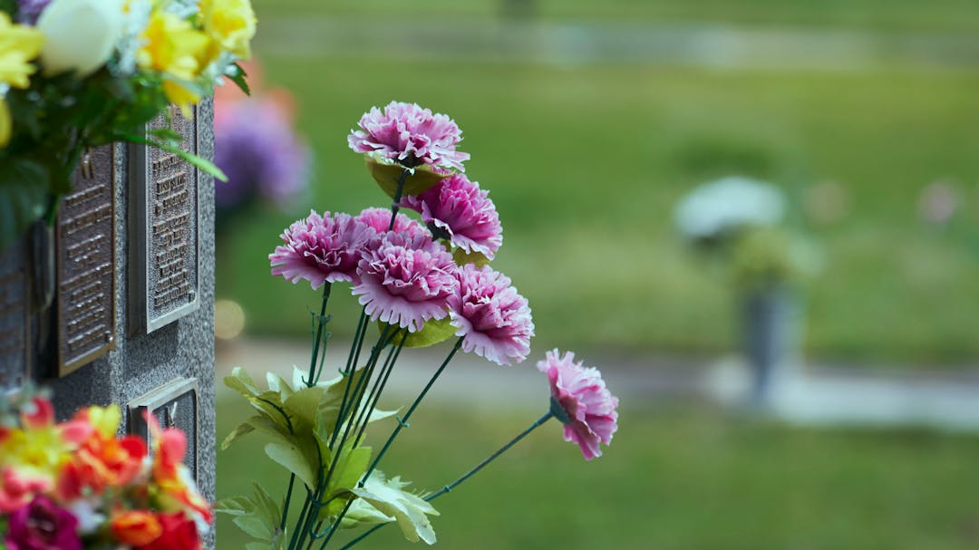 Columbarium wall with flowers and cemetery in background