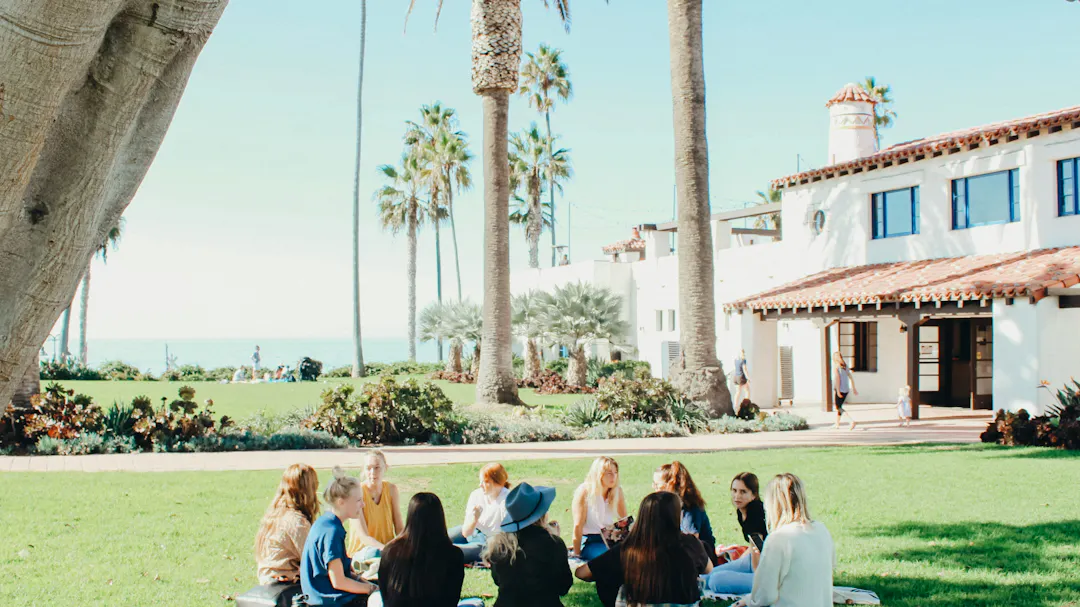 A group of students sit on the grass in a circle