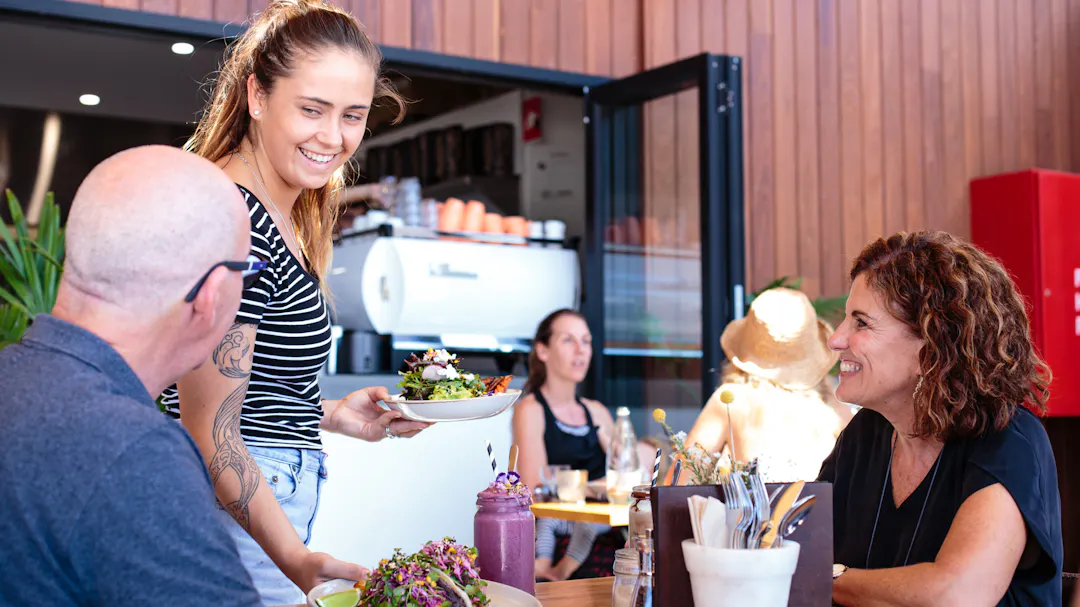 Waitress serving two diners at an outdoor café table
