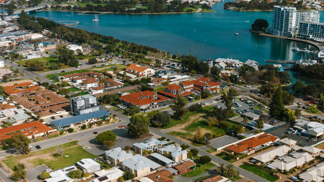 Aerial view of a coastal suburb with homes, canals, and waterways leading to the ocean on a clear day