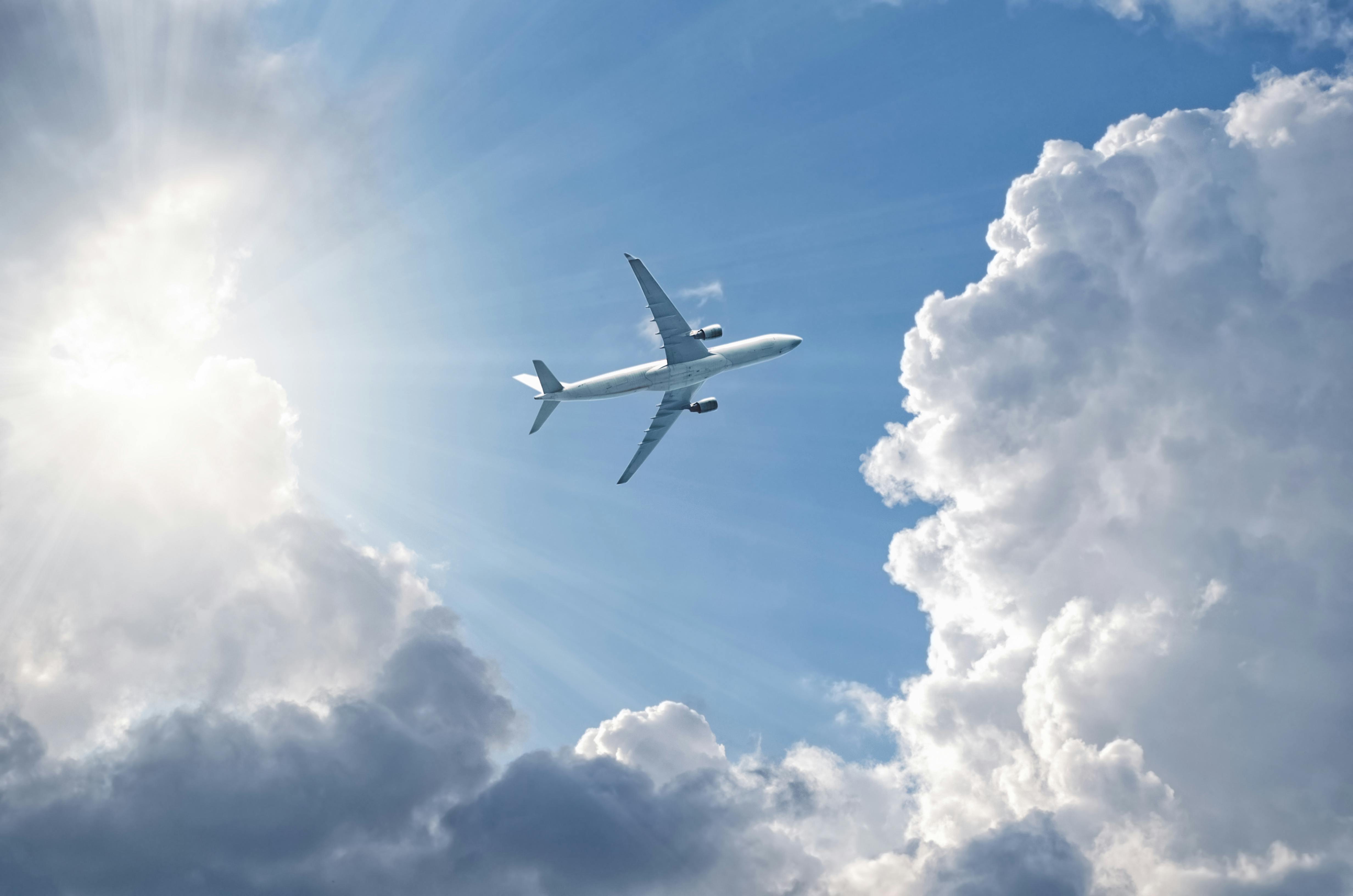 View from beneath of plane flying in blue sky and clouds