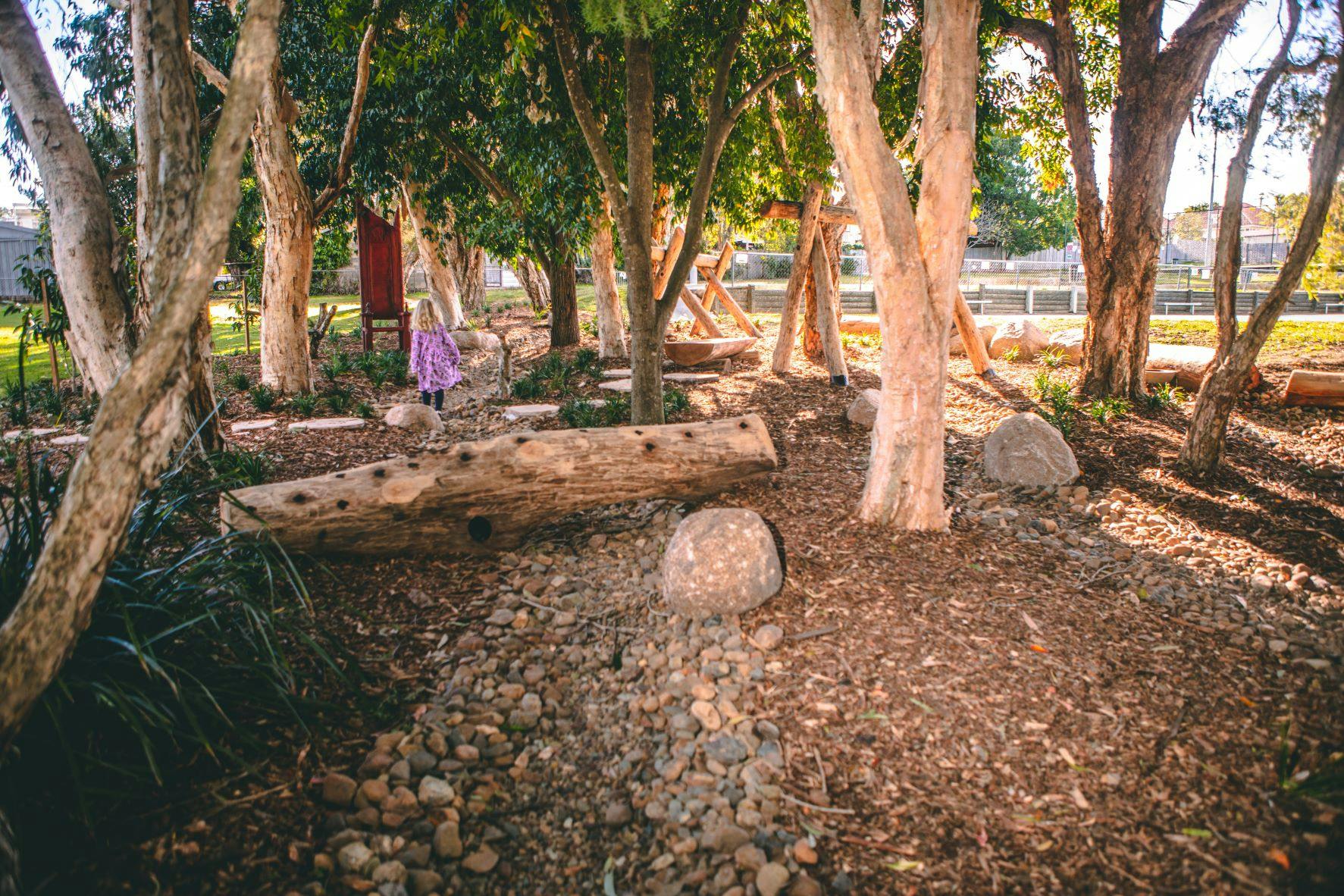 Girl exploring the nature play space, perhaps creating an imaginary world whilst exploring. 