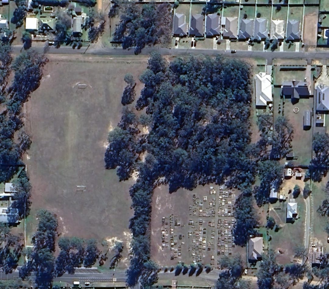 a satellite image of ellalong park a large patch of grass on the left, a patch of bushland with a cemetery below to the right