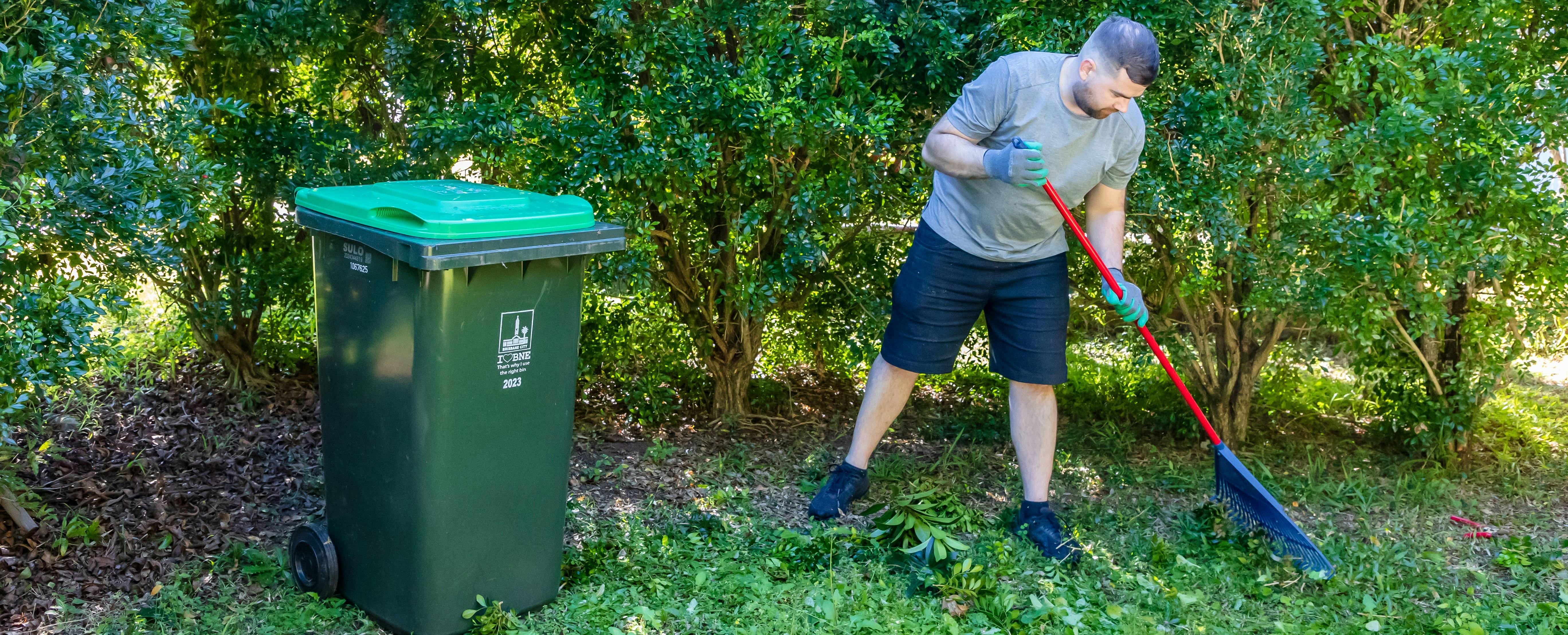 Person emptying food scraps from kitchen caddy into green waste recycling bin
