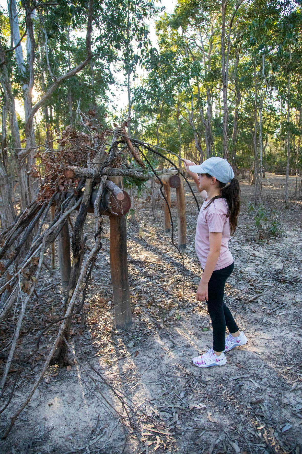 Girl gathering natural materials to create a cubby building or structure. 