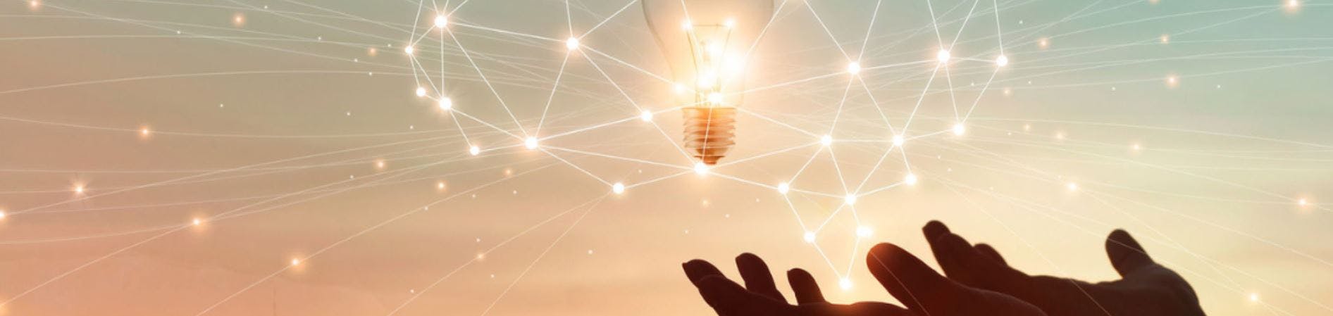 Image of hands cupping a lightbulb against a warm sky.