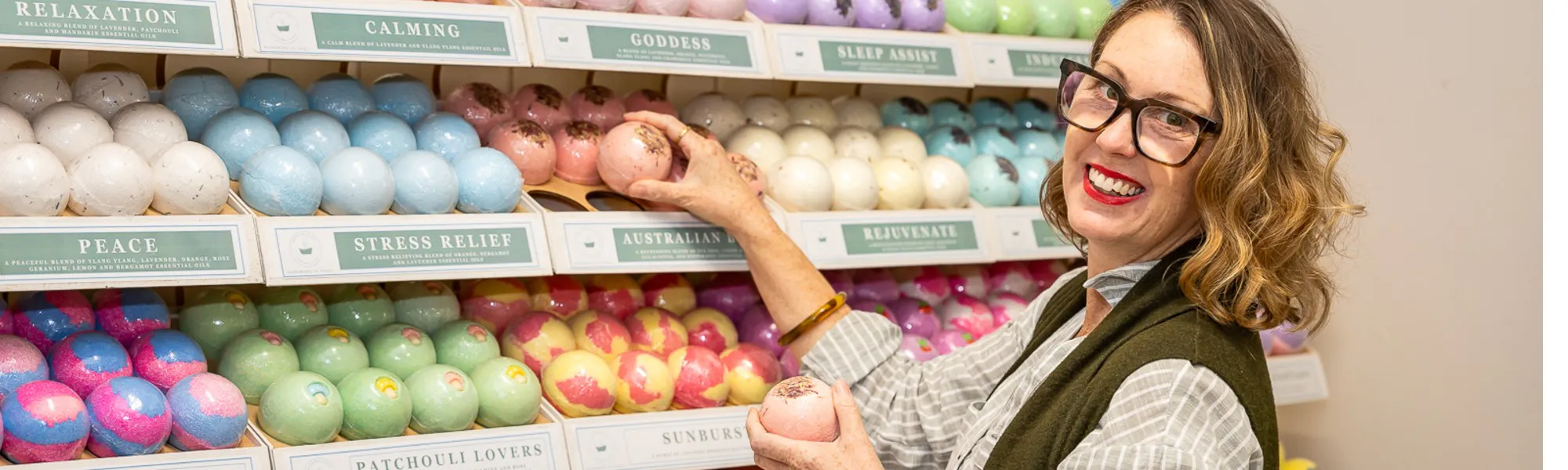 a woman holding colourful bath soaps at Tilba