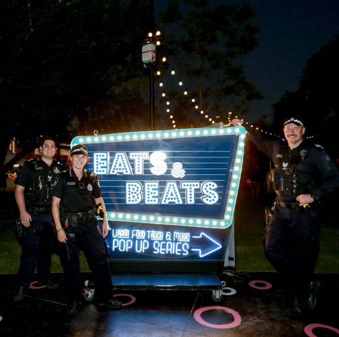  Police getting a photo Infront of Eats & Beats event sign 