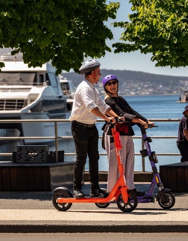 Two people riding e-scooters along the Hobart waterfront