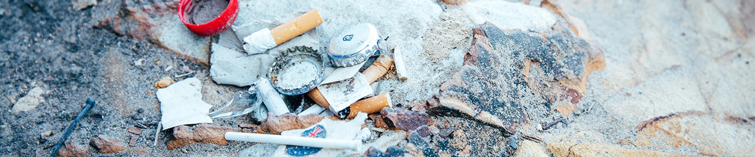 Cigarette butts, beer bottle lids and other rubbish on the ground