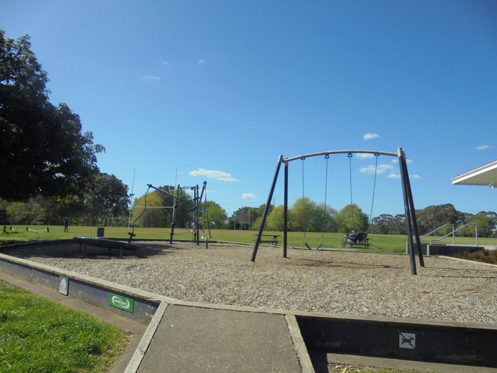 Ngāti Ōtara playground with sports fields in the back, provides ramp access to raised play space containing swings, spinner and basic module.