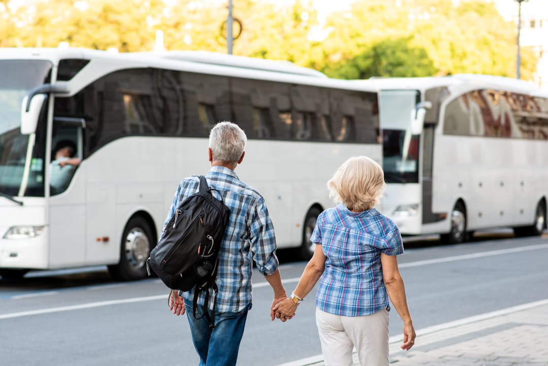 Couple walking together holding hands with busses in the background.
