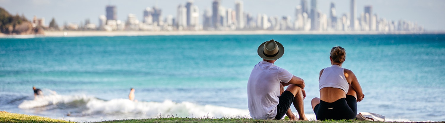 A young couple sitting on the Burleigh Headslands looking over the ocean towards Surfers Paradise