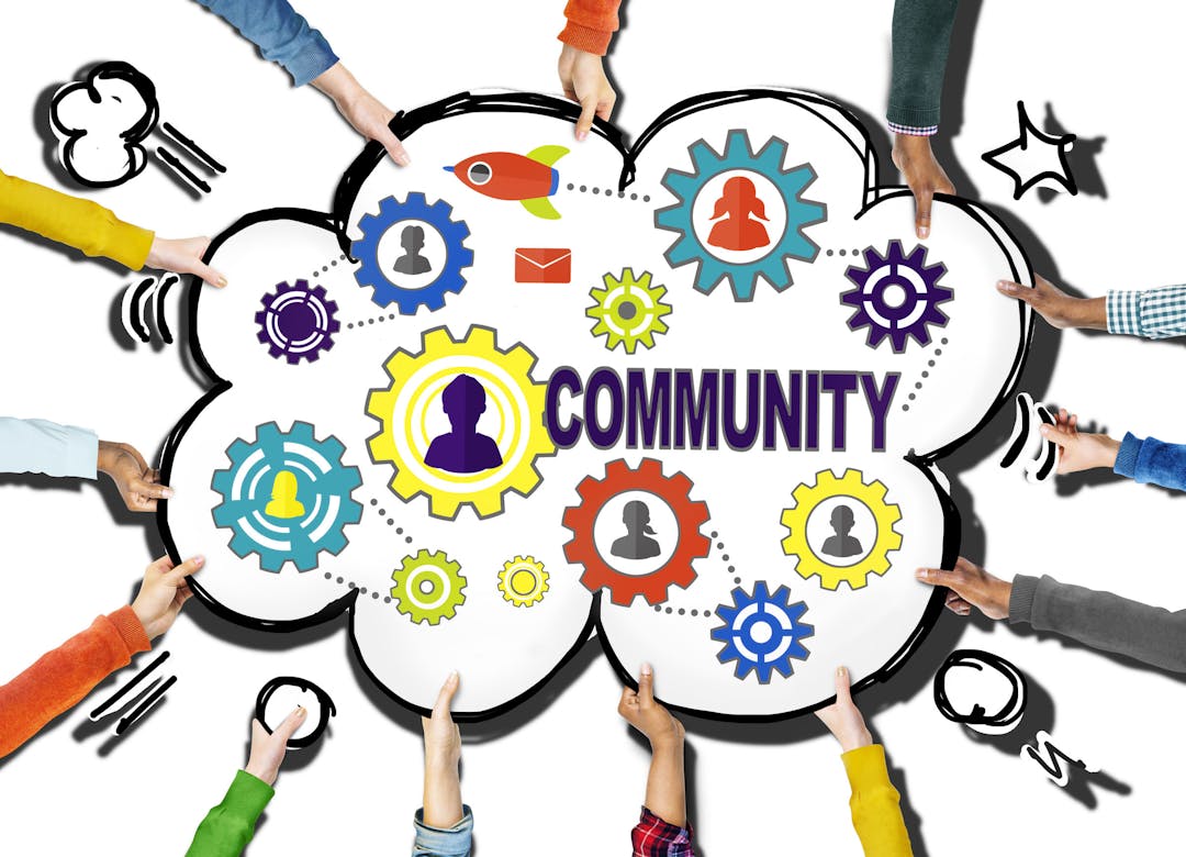cartoon cutout with cogs and 'community' written inside. Many hands are holding the cartoon sign up.