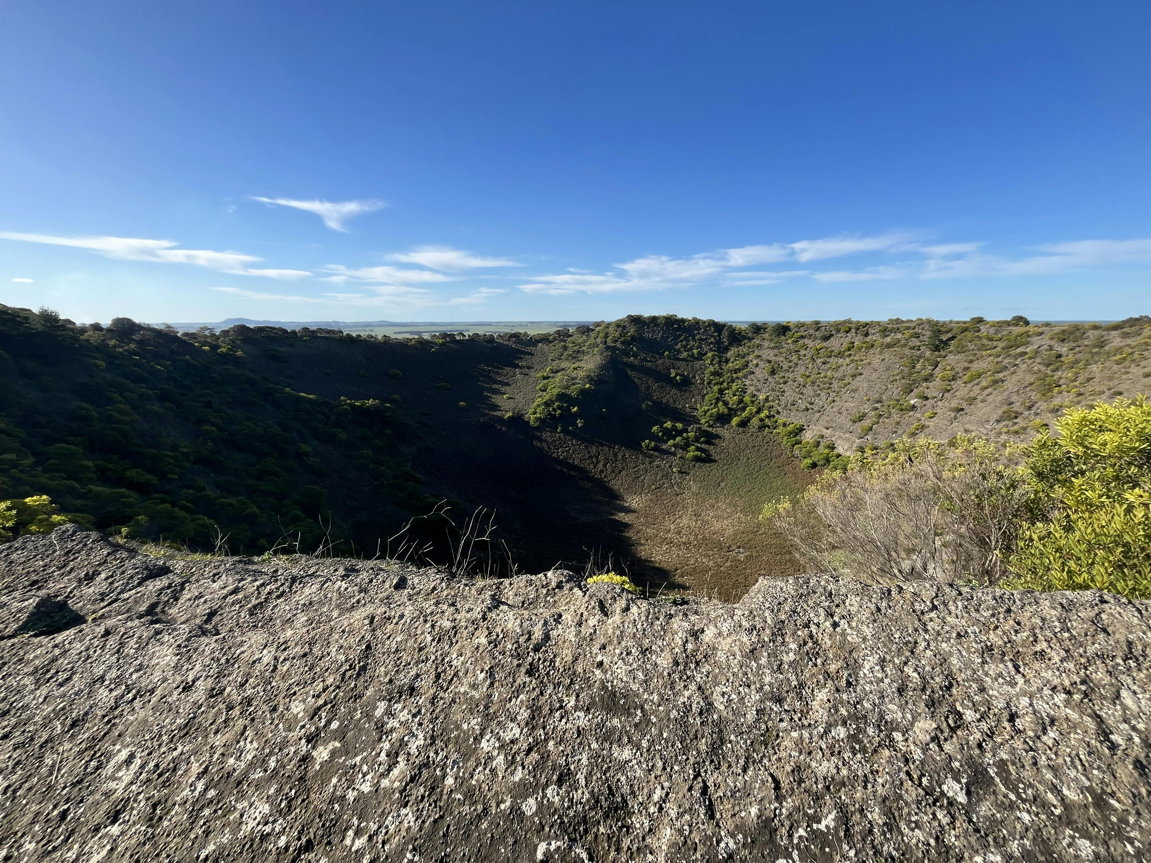 View across the rim and into an extinct volcano crater which has scattered low vegetation