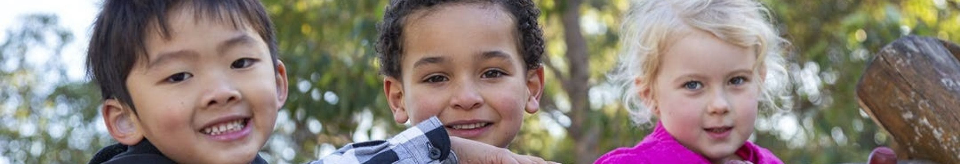 Three cute kids of mixed descent smiling 