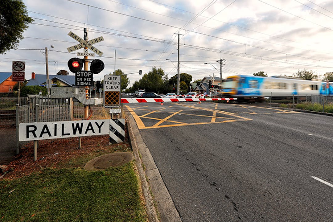 Train traveling through a level crossing at Grange Road in Alphington with the boom gate down
