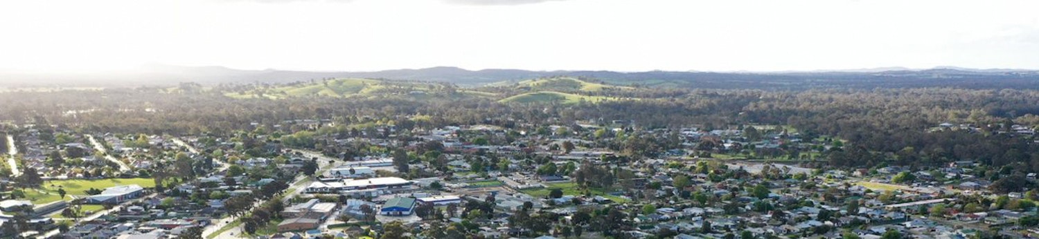 An aerial shot showing township in the foreground and green hills and mountains in the background