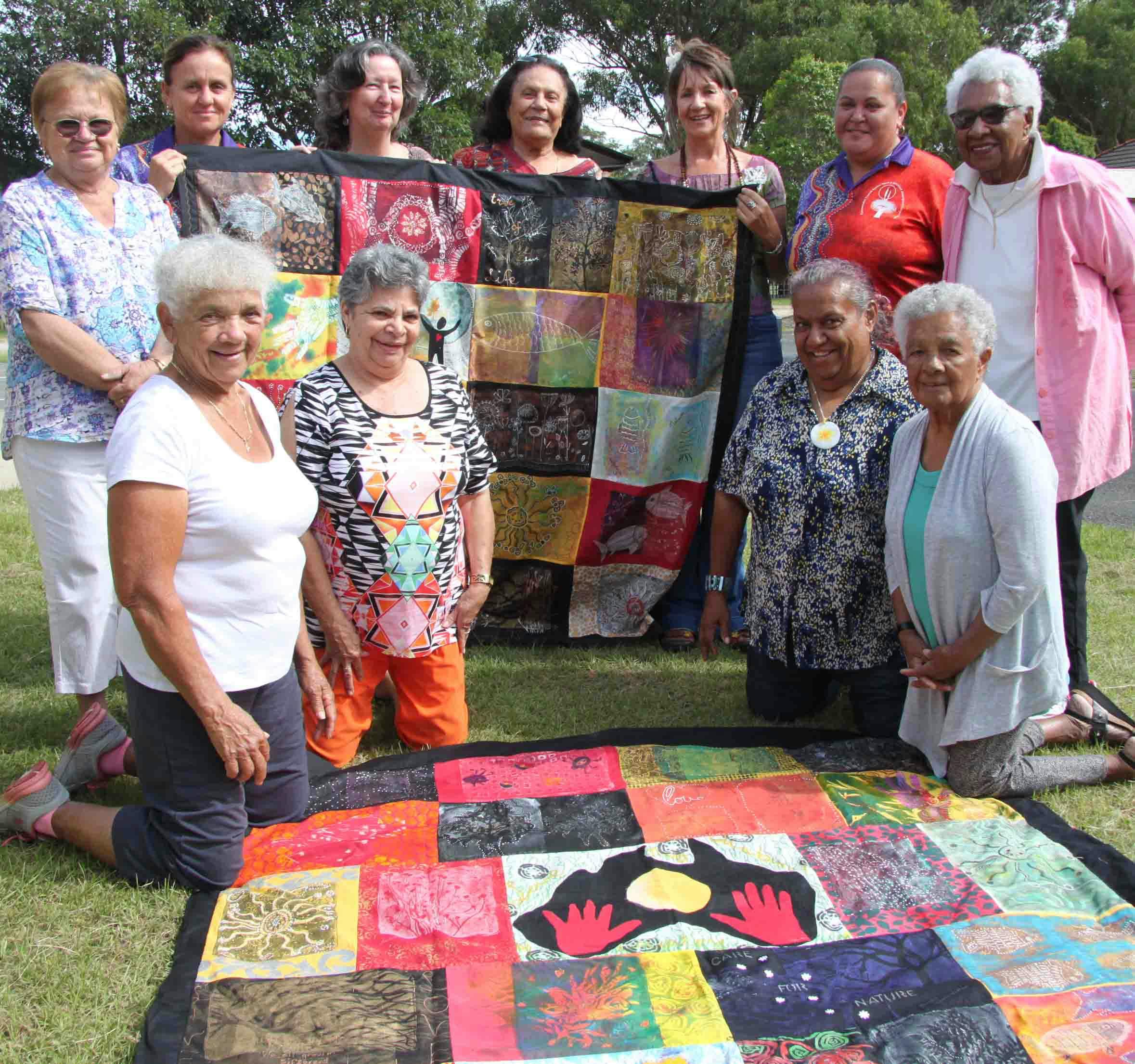 Participants in a Tweed Aboriginal Healthy Ageing Project with two tapestries they produced as part of the program.