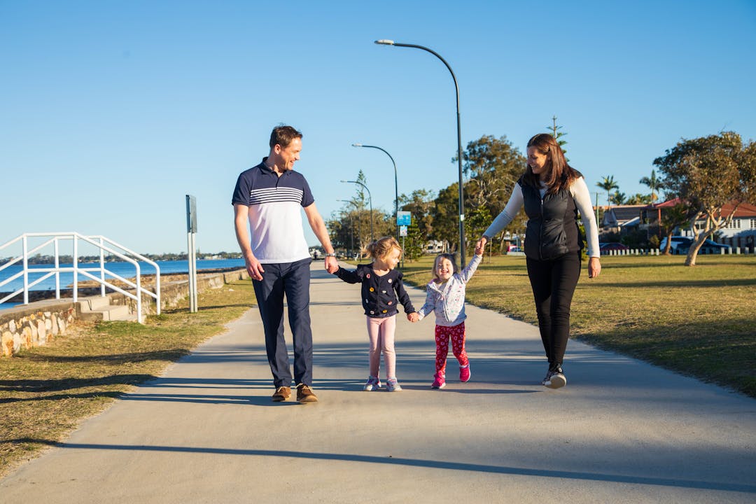 two people walking down a street under a large tree with red flowers