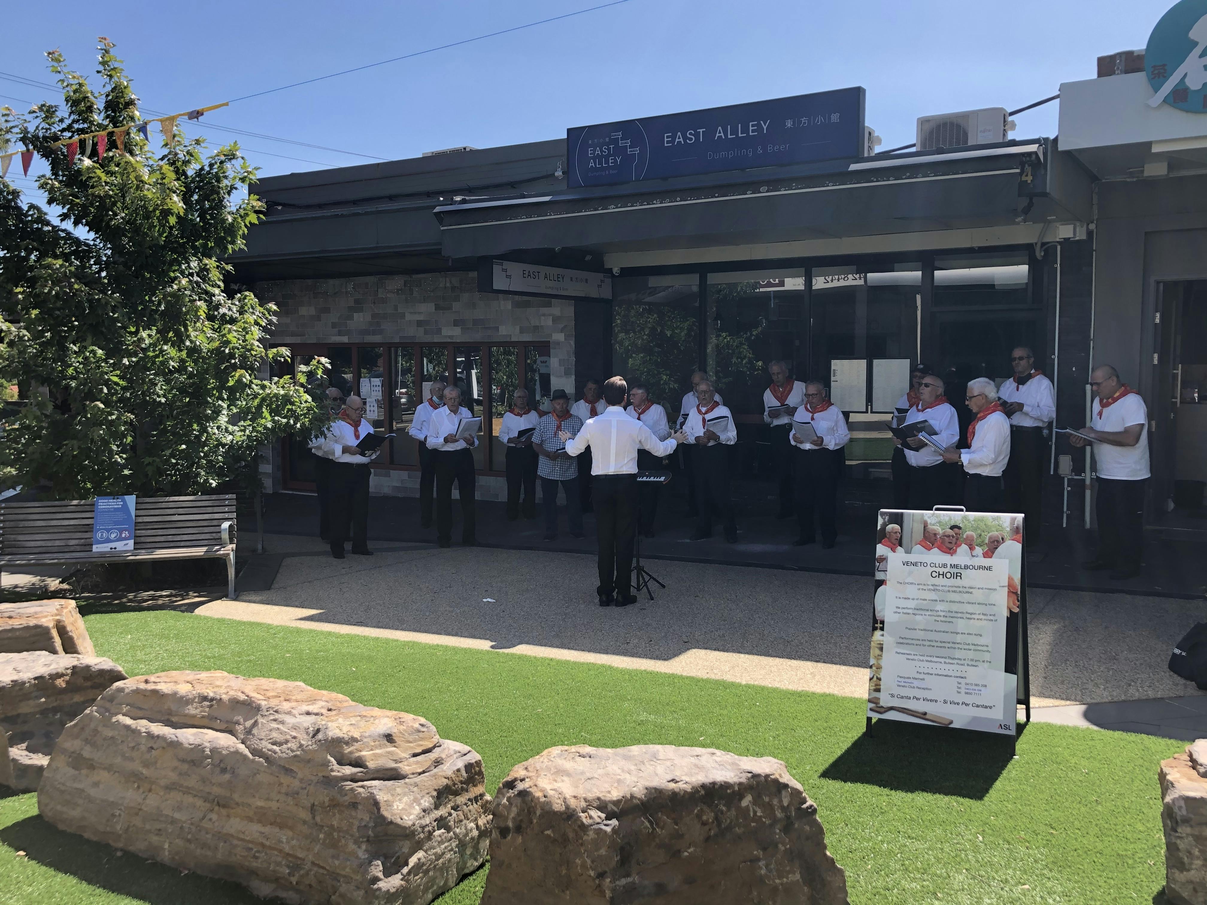Choir in white shirts singing at Tunstall Square