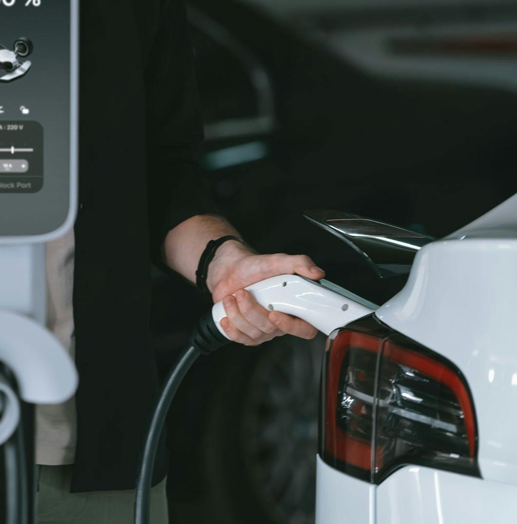 Photo of a hand plugging in the charger into an electric vehicle