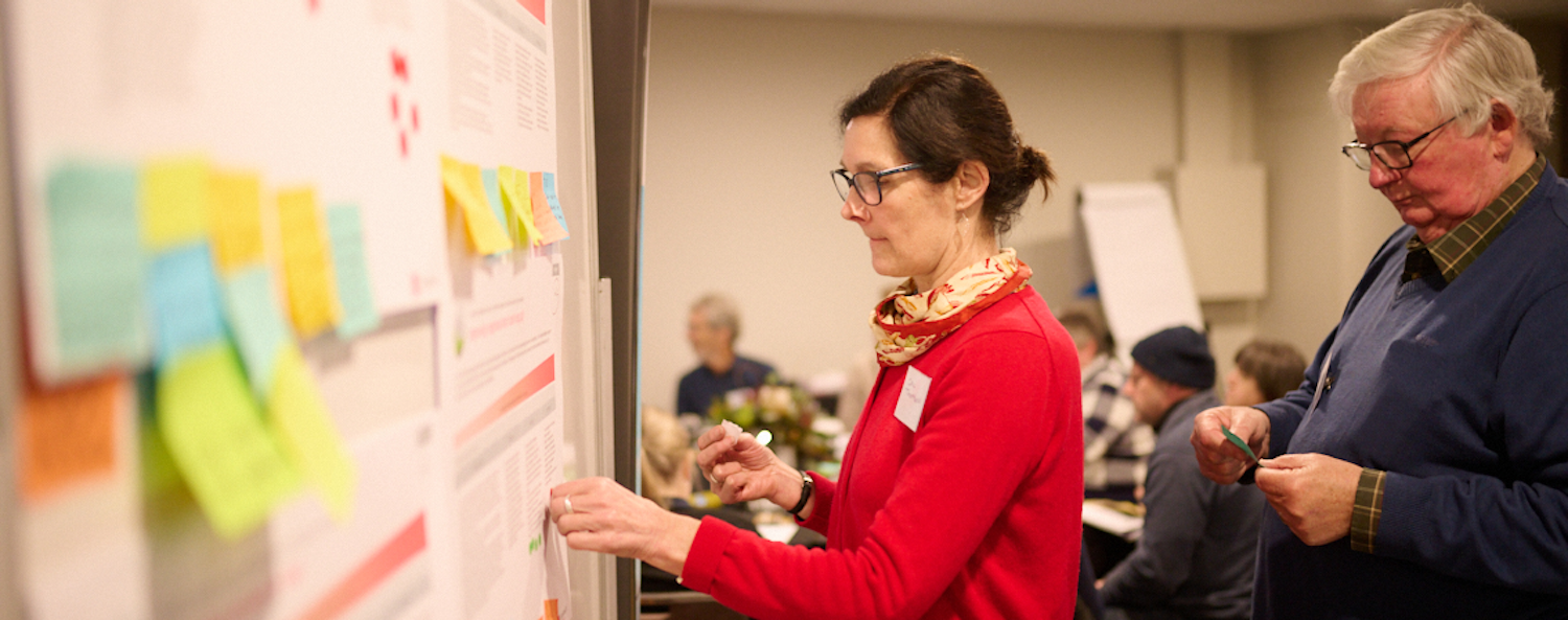 Summit participant providing feedback by sticking notes to the wall