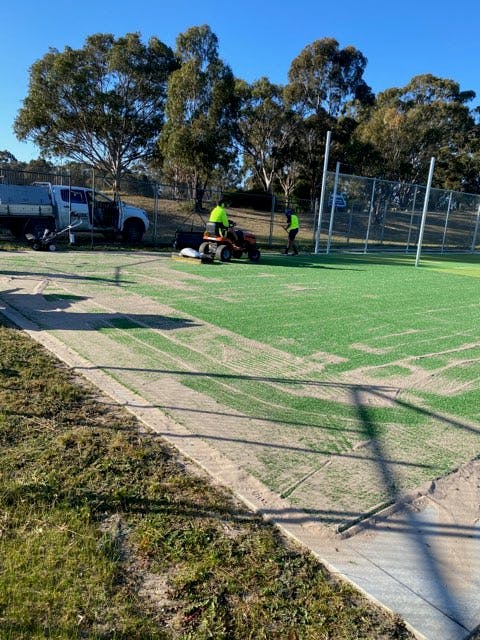 fine sand being pushed into the synthetic grass with machine