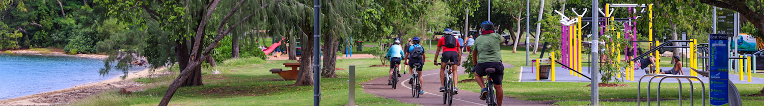 People biking on trail next to playground