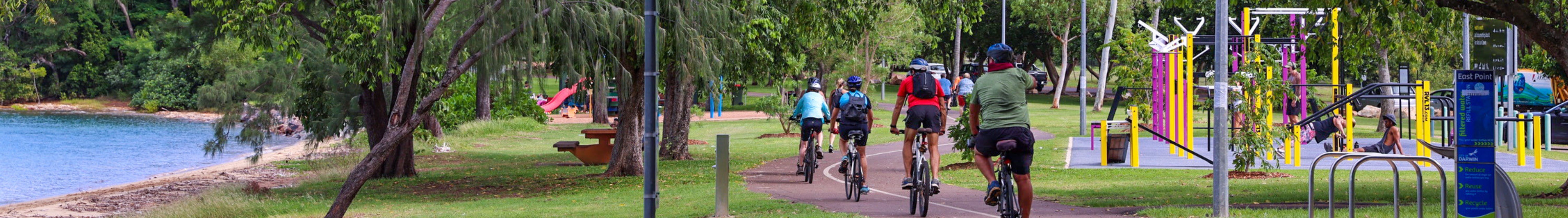 People biking on trail next to playground