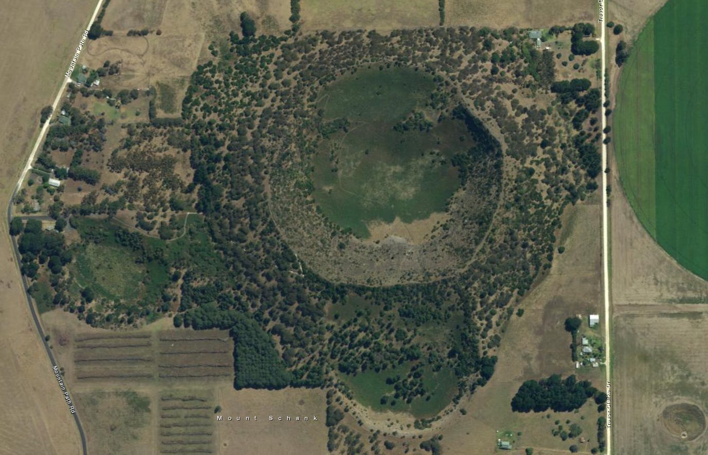Overhead view of landscape with extinct volcano crater that is covered in sparse, low vegetation